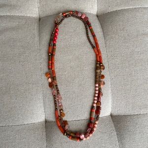 Single strand beaded necklace in shades of coral and bronze.